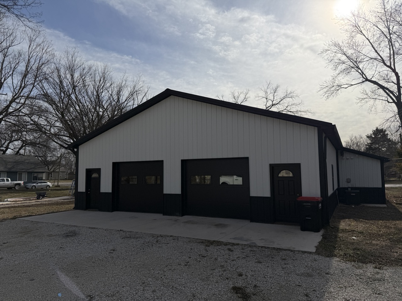 Front-facing exterior of a custom barndominium with multiple garage doors and metal siding built by Building Pros LLC in Kansas